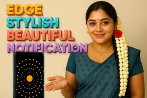 A woman, possibly actress Ramya, is shown from the chest up, with her right hand extended towards a smartphone in the lower left corner. She is wearing a teal-colored saree and a matching blouse, with a long strand of white jasmine flowers adorned with a single red rose tucked into her dark hair, which is styled over her left shoulder. She has a bindi on her forehead and a delicate gold necklace. The smartphone screen displays an orange circle with radiating yellow dots. To the left of the woman, large, colorful 3D text reads "EDGE," "STYLISH," "BEAUTIFUL," and "NOTIFICATION" in shades of orange, blue, red, and purple. The background is a plain light brown or beige.