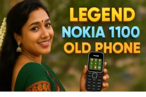 The image is a promotional graphic featuring a woman and a phone with overlaid text. On the left, a smiling woman with dark hair and a small bindi on her forehead looks towards the viewer. She is wearing a green saree with a red and gold patterned border and gold earrings. A garland of white flowers is visible in her hair on the far left. On the right, a black "Nokia 1100" style feature phone is held vertically, with its screen showing icons and its keypad visible. Large, bold yellow and blue text overlays the image, reading "LEGEND," "NOKIA 1100," and "OLD PHONE." The background is a blurred outdoor setting with green foliage.